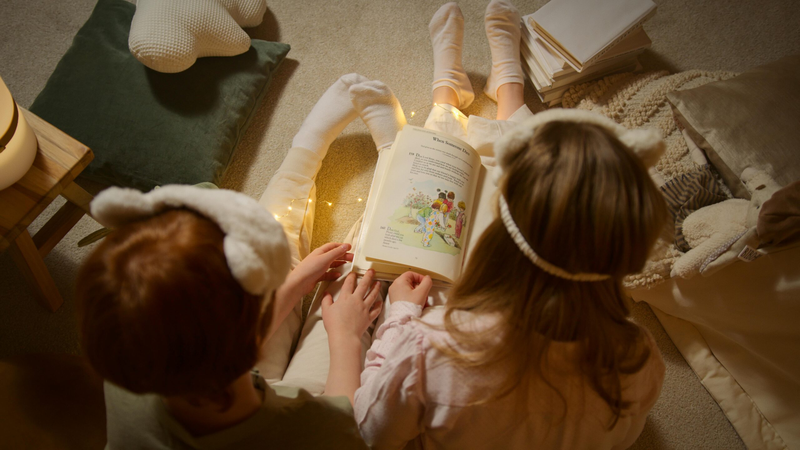 Two siblings enjoy a bedtime story with cozy string lights, fostering imagination and togetherness.